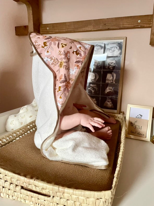 bébé portant la cape de bain motif Jardin Enchanté sur un tapis de change – JM Tout Doux