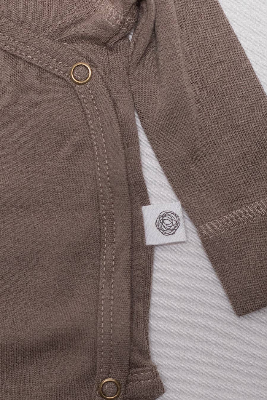 Gros plan sur l'étiquette d’un body bébé en laine mérinos non traitée, fibre respirante et naturelle Couleur : Noix