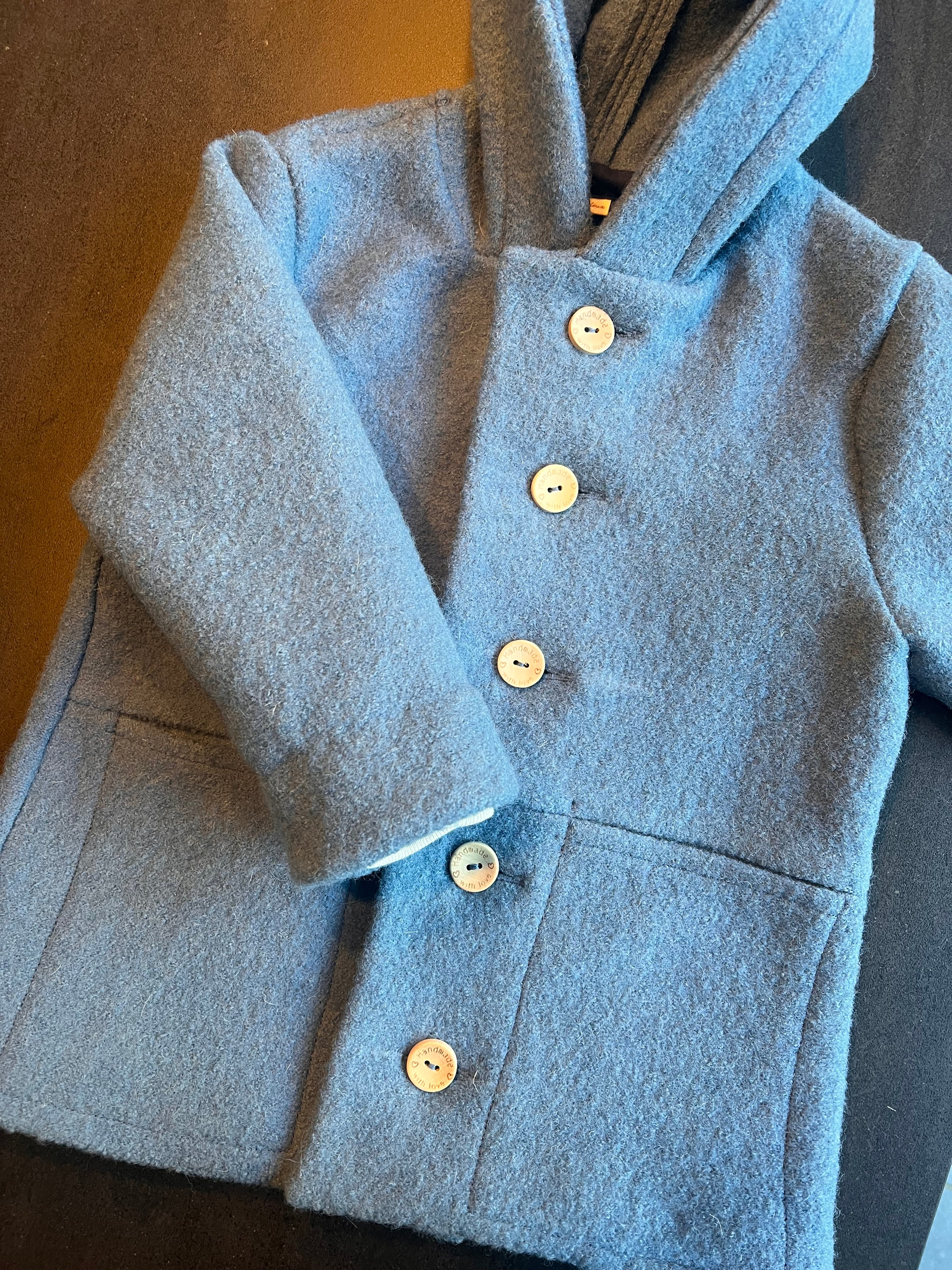 Détail des boutons cousus sur le manteau en laine, mettant en valeur les finitions soignées de cette création J'M tout doux.