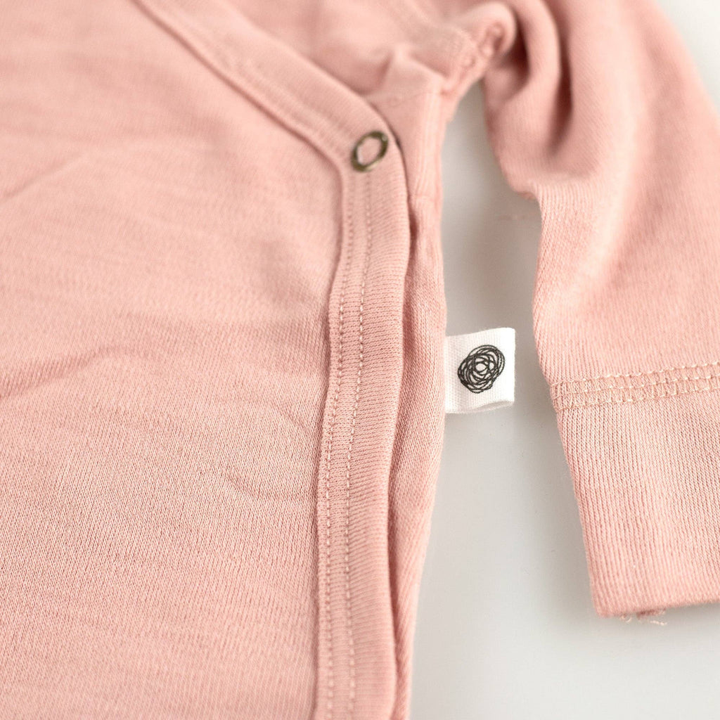 Détail sur l'étiquette de la fermeture par pressions d’un body bébé en laine mérinos non traitée, système doux et adapté à la peau sensible Couleur : Misty Rose