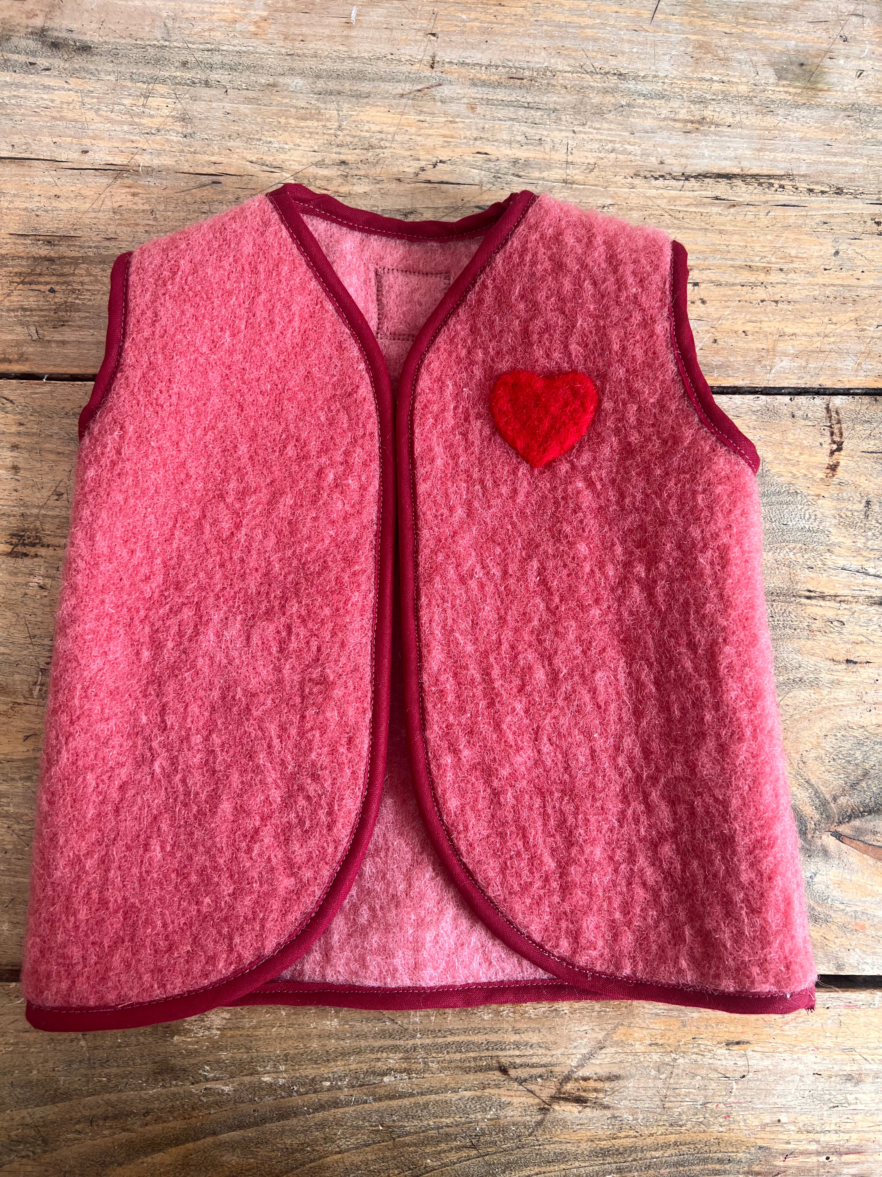 gilet sans manche en laine upcycler de couleur rose avec un coeur rouge sur la poitrine du côté gauche