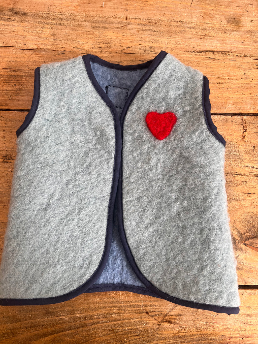 gilet sans manche en laine upcycler de couleur beu avec un coeur rouge sur la poitrine du côté gauche