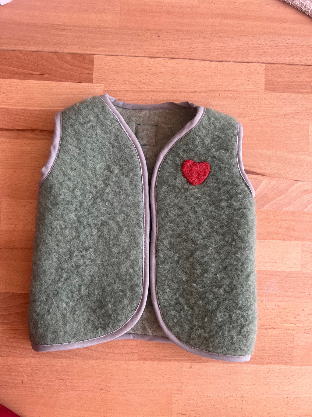   gilet sans manches en laine upcyclée de couleur verte avec un coeur rouge en laine cardée