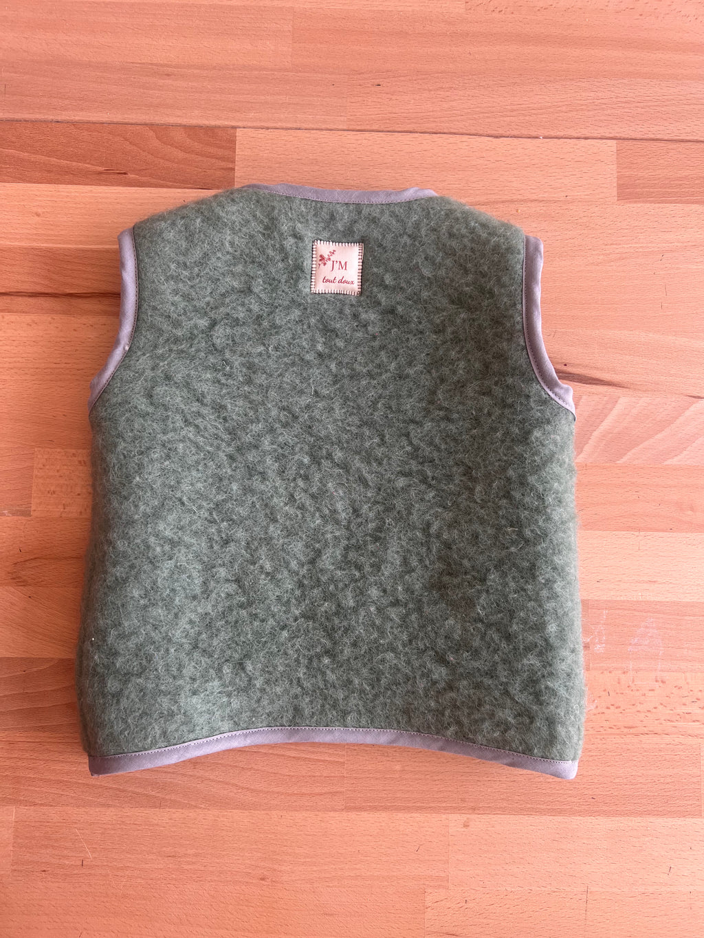  gilet sans manches en laine upcyclée de couleur verte avec un coeur rouge en laine cardée. vue de dos