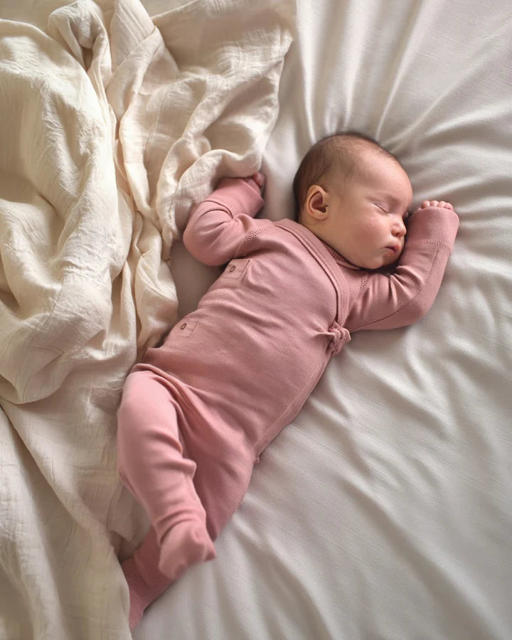 Bébé portant une combinaison en laine mérinos non traitée, idéale pour protéger du froid tout en laissant respirer la peau, couleur Misty Rose