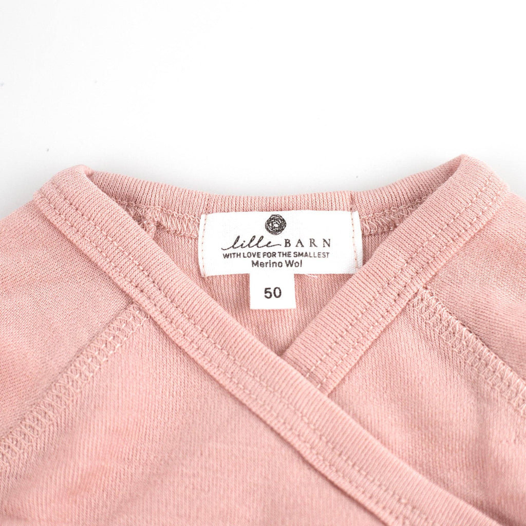 Gros plan sur la maille fine d’un body bébé en laine mérinos non traitée, fibre respirante et naturelle Couleur : Misty Rose