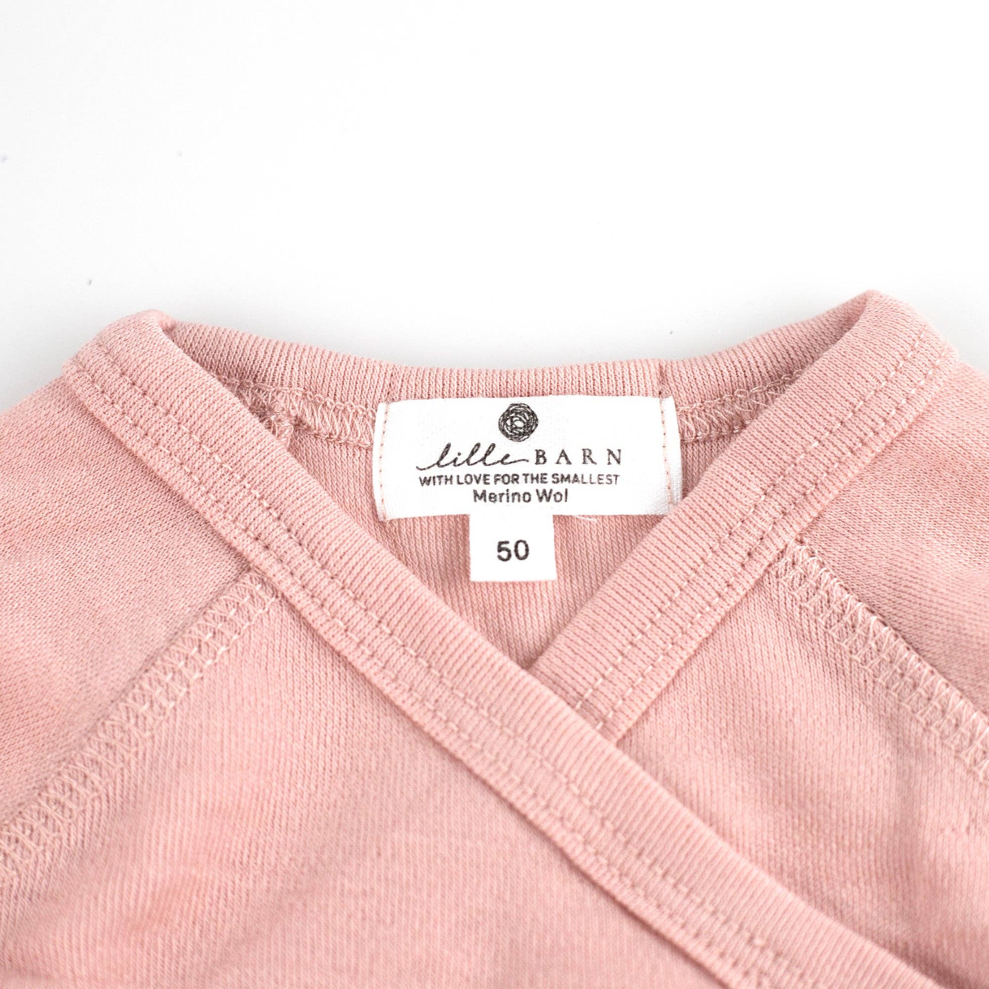 Gros plan sur la maille fine d’un body bébé en laine mérinos non traitée, fibre respirante et naturelle Couleur : Misty Rose